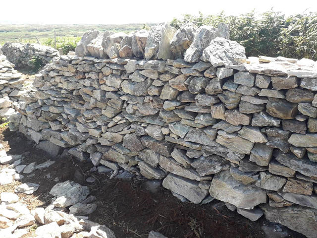 Rhan o'r wal wedi'i hatgyweirio gyda cherrig copa wedi'i chwblhau
