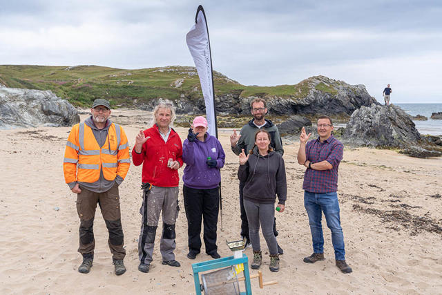 Gwirfoddolwyr a staff yn glanhau traeth Porth Dafarch